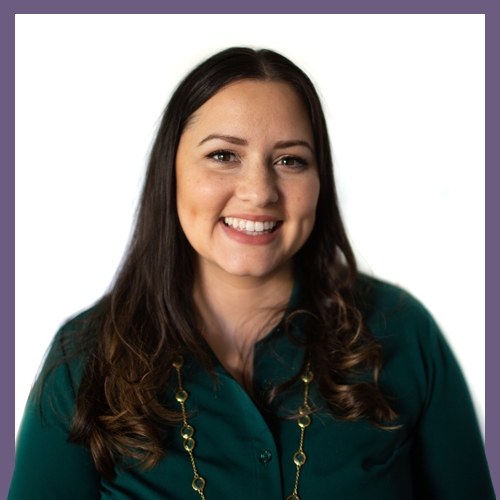 A woman with long dark hair, smiling, is wearing a green blouse and a gold chain necklace. She stands against a white background framed by a purple border.