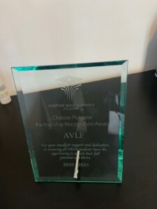 A glass award etched with "Purpose Built Schools Atlanta, Choose Purpose Partnership Recognition Award, AVLF, for your steadfast support and dedication to ensuring all PBSA students have the opportunity to reach their full potential and thrive. 2020/2021.