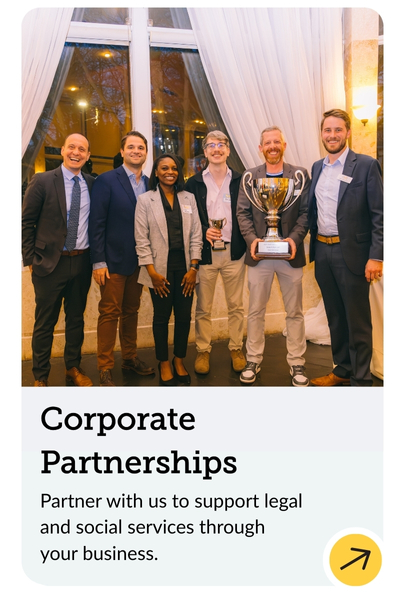 A group of six people in business attire stand indoors smiling. One person holds a large trophy. Below them is text about partnering for corporate support of legal and social services. The background features large windows with curtains.