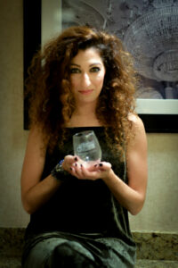 A woman with curly hair holds a glass award with text that reads 