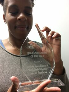 A person holding a crystal award that reads 