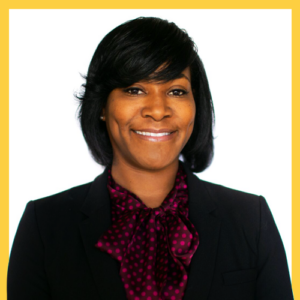 A woman with short black hair smiles while wearing a black blazer and a maroon polka-dotted blouse. The background is plain white, framed by a yellow border.