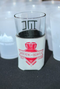 A glass with a beer-themed sleeve that reads 