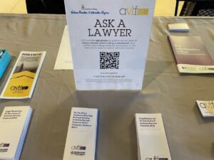A table display with brochures related to domestic violence and legal resources. A prominent sign reads 