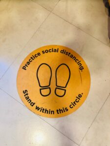 A yellow circular floor sticker with black footprints and text instructing to 