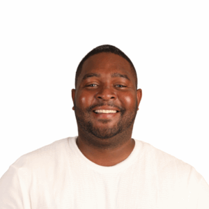 A smiling man with short hair and a beard wearing a white textured shirt, posing against a plain white background.