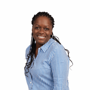 A woman with braided hair smiles at the camera. She is wearing a blue and white striped button-up shirt and hoop earrings, standing against a plain white background.
