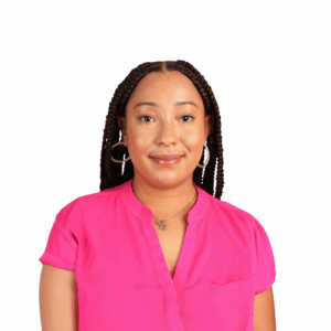 A woman with long braided hair smiles softly, wearing a bright pink short-sleeve blouse and hoop earrings against a plain white background.