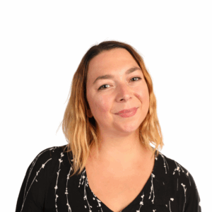 A woman with shoulder-length blonde hair wearing a black top with a white pattern smiles softly at the camera against a plain white background.