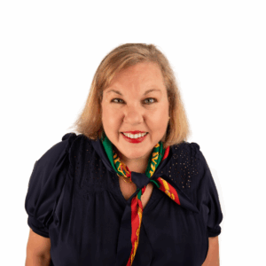 A smiling woman with shoulder-length blonde hair, wearing a navy blouse and a colorful scarf, poses against a plain white background.
