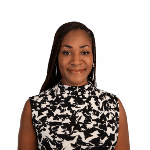 A woman with long braided hair smiles softly, wearing a sleeveless black and white patterned top, standing against a plain white background.