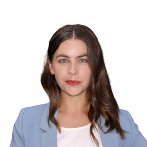 A woman with long brown hair and blue eyes wearing a light blue blazer and white top, looking directly at the camera against a plain white background.
